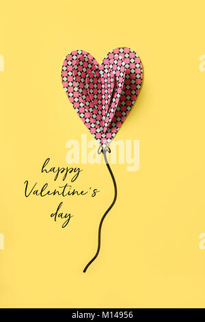 Hohe Aufnahme von einige bunte Ausschnitt Herzen und eine Zeichenfolge erstellt einen Ballon simuliert, und der Text happy valentines Tag auf gelbem Hintergrund Stockfoto