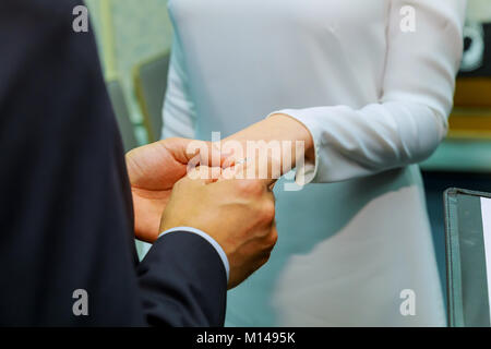 des Bräutigams Hand setzen einen Ehering am Finger der Braut Stockfoto