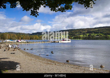 Coniston, Großbritannien - 14.. September 2011: In der Herbstsonne wartet ein Sightseeing-Boot auf Passagiere, die von einem Anlegesteg in der Nähe des Dorfes Coniston auf dem Coniston Water im Lake District National Park, Cumbria, Großbritannien, an Bord gehen. Coniston Water ist der drittgrößte See im englischen Lake District. Stockfoto