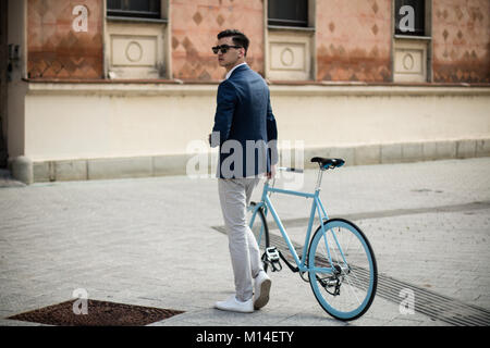 Elegante junge Mann mit blauen Fahrrad draußen auf der Straße Stockfoto