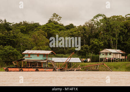 Einige Häuser entlang des Amazonas, das einzige Verkehrsmittel ist das Netz der Flüsse in der Gegend. Ein lastkahn im Vordergrund. Stockfoto