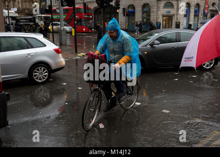 Ein Radfahrer vermeidet Fußgänger als Sturm Georgina fegte über Teile von Großbritannien und in Central London, mittags im Büro wurden durch sintflutartige Regenfälle und starke Winde gefangen, am 24. Januar 2018 in London, England. Fußgänger Zuflucht zu springen über tiefe Pfützen, an der Kreuzung von Oxford Street und der Kingsway in Holborn, die durch die Kanalisation überläuft. Stockfoto