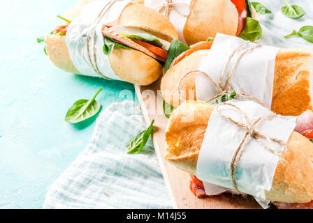 Frisches Baguette Sandwich mit Schinken, Käse, Tomaten und Spinat, hellblauer Hintergrund Kopie Raum Stockfoto