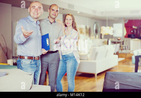 Verkäufer helfen jungen Paar neue Sofa für zu Hause wählen. Stockfoto