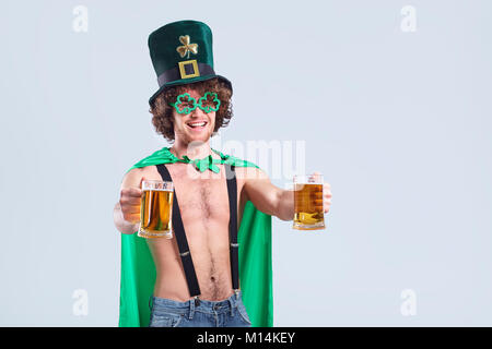 Eine junge Lockigen dunkelhaarigen Mann im Anzug von St. Patrick mit einem Becher o Stockfoto