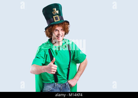 Eine junge Lockigen dunkelhaarigen Mann in St. Patrick's Anzug zeigt seine Finger. Stockfoto