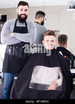 Gerne erwachsenen männlichen Friseur Haarschnitt zum Client angezeigt, die im Friseursalon Stockfoto