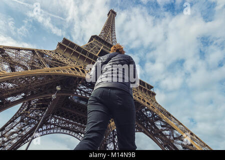 Frau geht unter dem Eiffelturm in Paris. Stockfoto