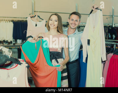 Junge Frau und Mann auf der Suche nach neuen Kleid im Showroom Stockfoto