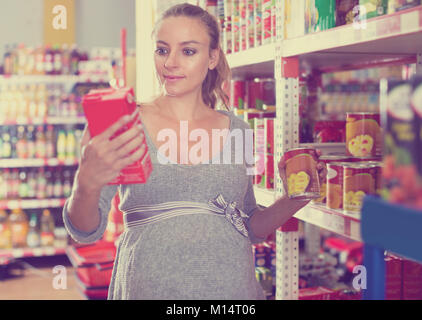 Glückliche Zukunft Mutter ist Lesen Struktur des Produktes auf den Regalen im Supermarkt Stockfoto