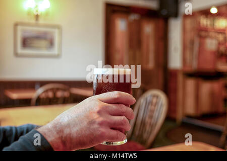 Mann hebt ein Pint Bier im Pub Stockfoto