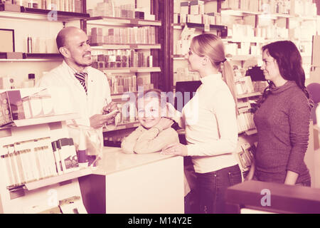 Positiven erwachsenen Apotheker mit einer Kasse in der Apotheke und Kunden helfen Stockfoto