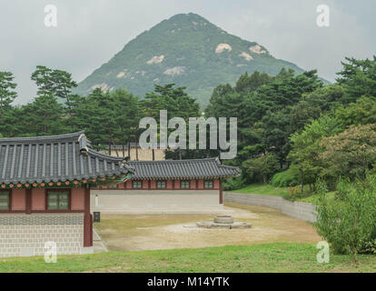 Alte Wohnungen mit ausgefallenen Dächer, Bäume und Rasen, mit einem Berg erhebt im Hintergrund, an den Gyeongbokgung Palast, Seoul, Südkorea Stockfoto