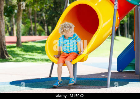 Kids klettern und rutschen auf Spielplatz im Freien. Kinder spielen im sonnigen Sommer Park. Aktivität und Amusement Center in Kindergarten oder Schule Hof. Chi Stockfoto