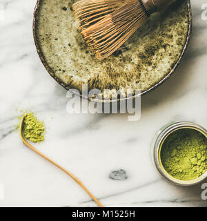 Flachbild-lay der japanischen Werkzeuge für die Zubereitung von Matcha Tee. Matcha Pulver in Blechdose, Chashaku Löffel, Chasen Bambusbesen, Chawan Schüssel, Tassen für Zeremonie, grau Stockfoto