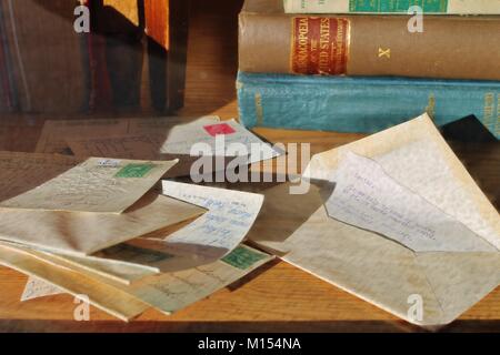 Stapel der alten frankierten Briefe und Umschläge mit antiken Büchern im Hintergrund Stockfoto