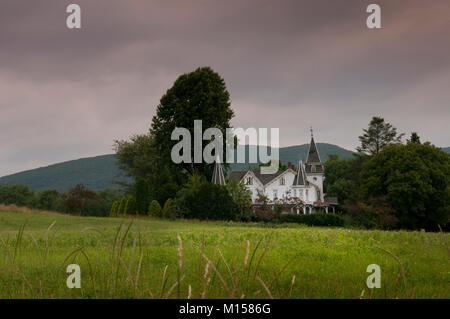 Moody Schuß im Gotischen Haus in grüne Felder und Bäume gegen stürmischen Himmel set isoliert Stockfoto