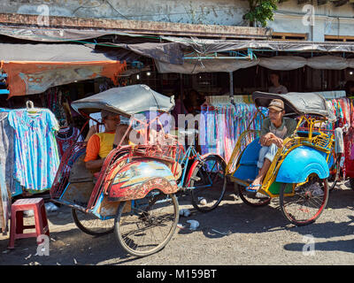 Zyklus Rikschas auf Kundschaft warten auf Malioboro Street entfernt. Yogyakarta, Java, Indonesien. Stockfoto