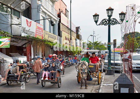 Zyklus Rikscha und Pferdekutsche entlang Malioboro Street entfernt. Yogyakarta, Java, Indonesien. Stockfoto