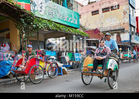 Cycle rickshaw mit seinem Passagier auf Malioboro Street entfernt. Yogyakarta, Java, Indonesien. Stockfoto