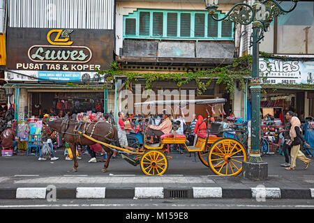 Pferdekutsche auf Kundschaft warten auf Malioboro Street entfernt. Yogyakarta, Java, Indonesien. Stockfoto