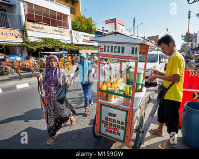 Muslimische Frauen zu Fuß durch Straßenhändler verkaufen frische Fruchtsäfte auf Malioboro Street entfernt. Yogyakarta, Java, Indonesien. Stockfoto