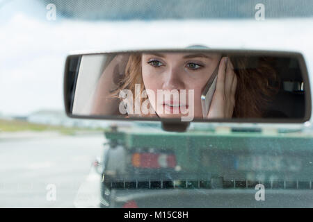 Eine junge Frau fährt ein Auto und Gespräche am Telefon und ist abgelenkt Stockfoto