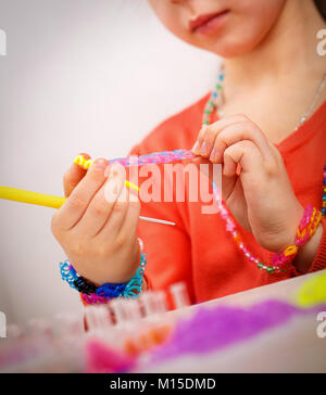 Mädchen webt Schmuck Armband Gummi, Gummi weben, Hobby auf einem hellen Hintergrund Stockfoto