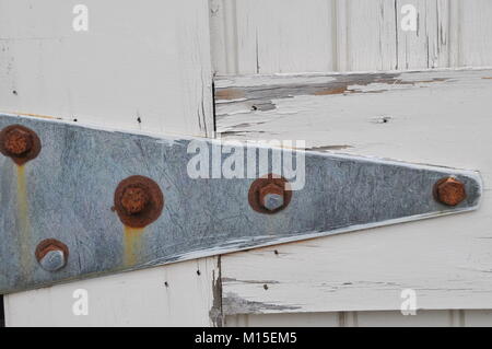 Verrostete Scharniere aus Metall auf einem weißen Scheunentor Stockfoto