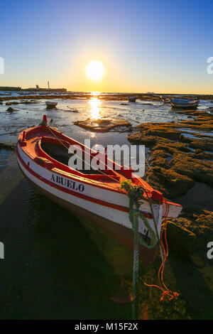 Rot und Weiß Holz- Boot gebunden bei Sonnenuntergang und Ebbe. Hochformat. Stockfoto