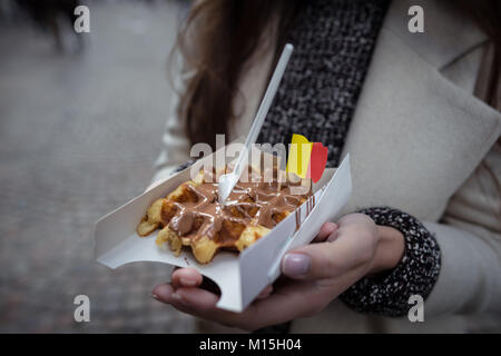 Belgische Waffeln mit der Nationalflagge in der jungen Frau Hände eingerichtet. Nähe zu sehen. Händen hält frische Waffeln mit Milchschokolade. Stockfoto