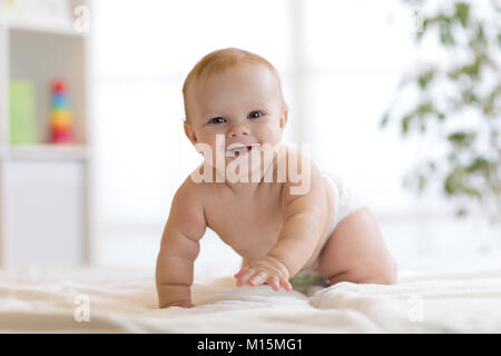 Lustige baby boy getragen Windel krabbeln auf dem Bett zu Hause. Stockfoto