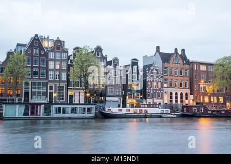 Amsterdam, Niederlande - 21 April, 2017: Blick auf typische Amsterdamer Häuser entlang Kanal an bewölkten Himmel. Segelboote haben Touren auf Grachten von Amsterdam. Stockfoto