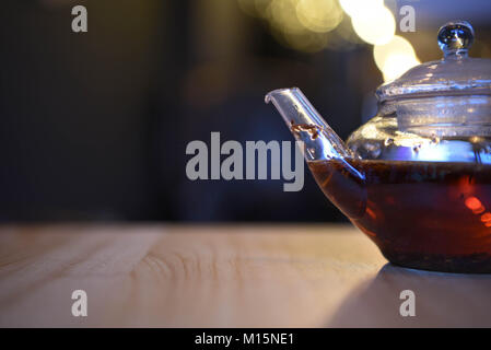 Trinken Bild von einem heißen Tee in eine Teekanne aus Glas und mit Bokeh, verschwommenen hellen Hintergrund und Tee aromatisiert mit Fruit Strawberry kiwi Apple und Spice Stockfoto