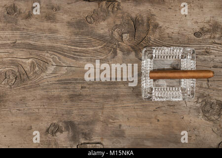 Zigarre in einem Aschenbecher auf einer hölzernen Oberfläche, mit einem Platz für Ihren Text. Ansicht von oben Stockfoto