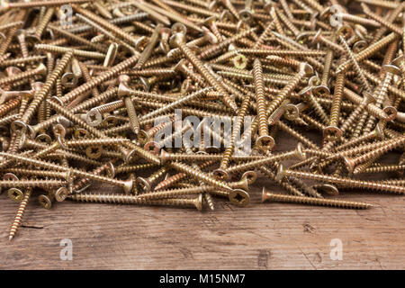 Rahmen aus neuen silbernen Schrauben liegen auf einem Holz- Oberfläche. Mit Platz für Text Stockfoto