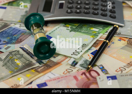 Geschäft Hintergrund. Taschenrechner, Stift und Sanduhr liegen auf dem Hintergrund des Geldes. Close-up Stockfoto