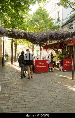 Montmartre, Paris, Frankreich. Ein paar Hand in Hand gehen Sie in Richtung Café Terrasse an einem sonnigen Abend, halten sich an den Händen Stockfoto