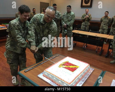 Al Udeid AIR BASE, Katar - Pvt. Frika Ryman (links) und Chief Warrant Officer 3 Anthony Martinez (rechts), die ihr die jüngsten und ältesten Soldat 5. zugeordnet, 52nd Air Defense Artillery' Team Deuce 'Regiment, 11 Air Defense Artillery Brigade, schneiden Sie den Kuchen in der Anerkennung der Übertragung der Befehlsgewalt zwischen dem 5-52 und dem 2-43 rd ADA ADA "Krieger" Regiment, 11 ADA am Blatchford-Preston komplexe Theater auf Al Udeid Air Base, Katar, Jan. 12, 2018. Stockfoto