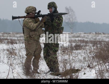 Ein rumänischer Soldat (rechts), um die rumänische Armee Boden Base Air Defence Loslösung, schwarzen Fledermäusen zugeordnet, lädt eine Granate in die Rakete angetrieben Granatwerfer für Sgt. Stephen Lennon (links), ein Soldat an die Zentrale und Hauptverwaltung Truppe, 3 Staffel, 2. Kavallerie Regiments, zugeordnet in einem Bereich in der Nähe der Bemowo Piskie, Polen, Jan. 24, 2018. Die einzigartige, multinationalen Battle Group, bestehend aus USA, Großbritannien, Kroatischen und Rumänische Soldaten dienen, die mit der polnischen 15 mechanisierte Brigade als Abschreckung Kraft im Nordosten Polens in der Unterstützung der NATO-Präsenz verstärkt nach vorne. Stockfoto