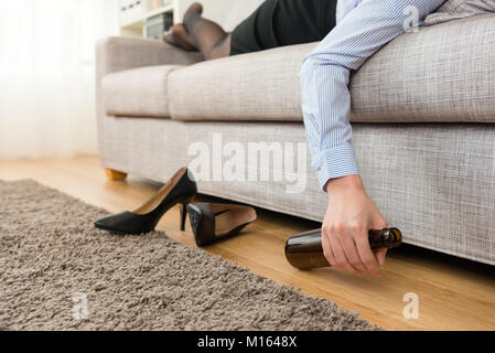 Nahaufnahme der Business woman take off High Heel Schuhe liegen auf dem Sofa und trinken Bier. Stockfoto