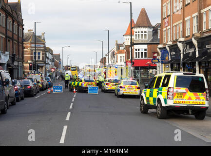Sanitäter Laden eines Unfallopfers in einem NHS Krankenwagen mit Polizei Autos im Vordergrund. Stockfoto