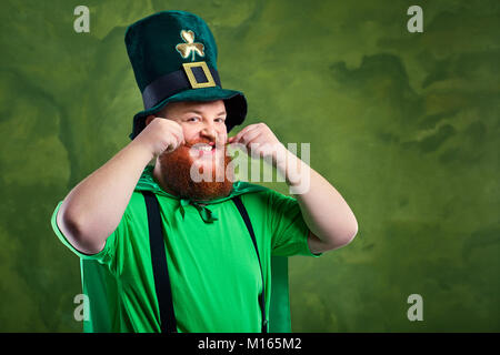 Ein dicker Mann mit Bart in St. Patrick's Suit ist ein Lächeln auf den Lippen. Stockfoto