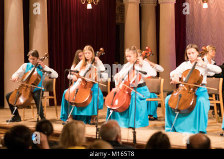 Eine Gruppe von jungen Cellisten spielt auf der Bühne. Unter dem octoponiment des fortopian. Verschwommen Stockfoto