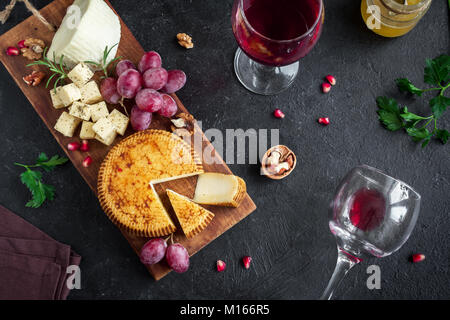 Käseplatte mit verschiedenen Käsesorten, Trauben, Nüsse über schwarzen Hintergrund, kopieren. Italienischen Käse und Obstteller mit Honig und Wein. Stockfoto