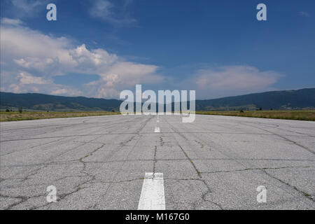 Abgebrochene Landebahn als Rallye Rennstrecke verwendet. Heißen Sommertag. Risse und Auto Reifenspuren auf dem Asphalt Oberfläche gesehen Stockfoto