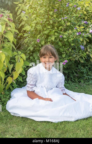 Portrait von lächelnden Mädchen in weißen Brautjungfer Kleider Sitzen im Freien. Stockfoto