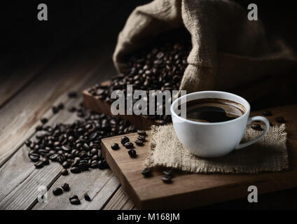 Kaffeetassen und Kaffeebohnen auf einem Holztisch Stockfoto