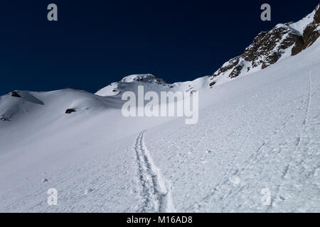 Ein Track über neue unberührten Pulverschnee führenden über Schnee in Richtung Alpine Mountain Pass an sonnigen bluebird Tag im Winter gemacht Stockfoto