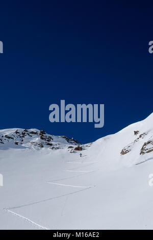 Ein skitourengeher der ersten Spuren im frischen Powder auf dem Weg bis zu hochalpinen Pass an sonnigen bluebird Tag Stockfoto